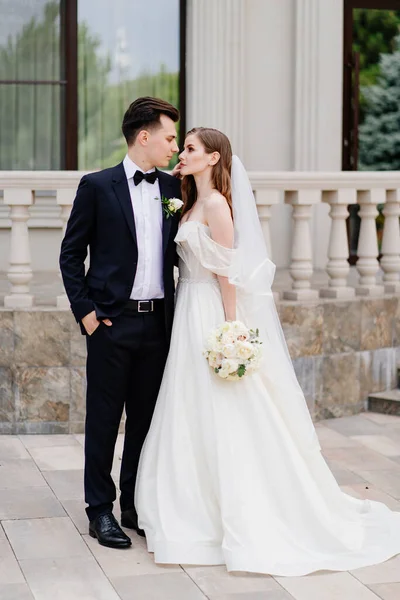 Bellissimi sposi stare sullo sfondo di un edificio leggero. — Foto Stock