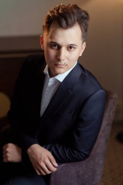 Beyaz gömlekli ve siyah ceketli genç adam sandalyede oturuyor. iş portresi