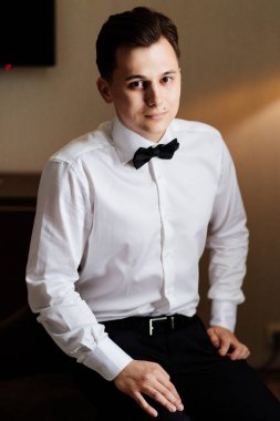 Beyaz gömlekli ve papyonlu genç adam sandalyede oturuyor. iş portresi