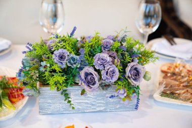 Şenlikli yemek masasında ahşap bir kutuda mor çiçekler.. 