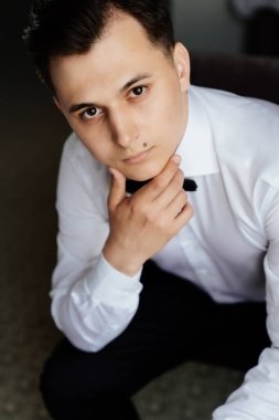 Beyaz gömlekli ve papyonlu genç adam sandalyede oturuyor. iş portresi