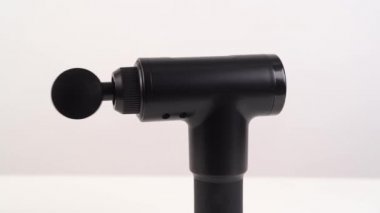 Beyaz bir arka planda çalışan, dönen bir masaj silahı. tıbbi spor aygıtı. 