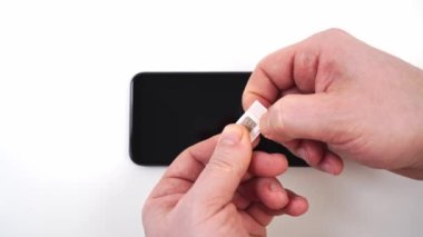 Erkekler, adaptör mini sim karttan bir nano sim kart çıkarır.. 
