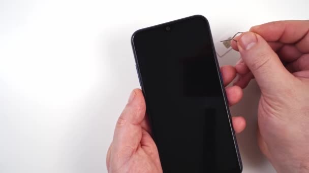 Männerhand steckt eine SIM-Karte in ein Smartphone — Stockvideo
