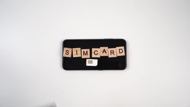 SIM karta a nápis na kostkách jsou na smartphonu a dolarových bankovkách. — Stock video