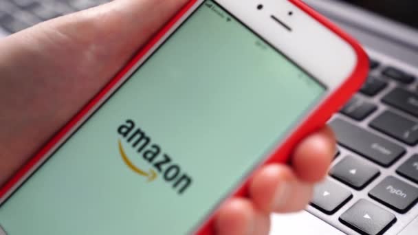 Amazon. iPhone elinde dizüstü bilgisayarın önünde. Akıllı telefona uygulama yükleniyor. — Stok video