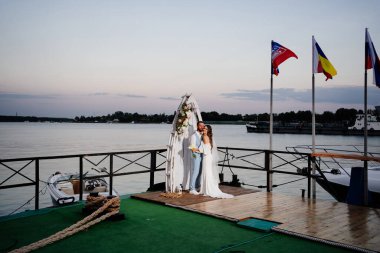 Rıhtımda suyun kenarında güzel bir düğün töreni. gelin ve damat.