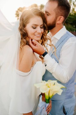 Güneş parlaması. Uzun bukleli, beyaz, zarif elbiseli, zambaklı gelin..