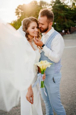 Güneş parlaması. Uzun bukleli, beyaz, zarif elbiseli, zambaklı gelin..