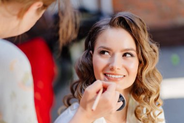 Makyaj sanatçısı evin bahçesinde geline makyaj yapıyor.