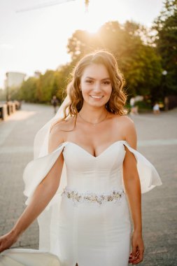 Güneş parlaması. Uzun bukleli beyaz elbiseli gelin.