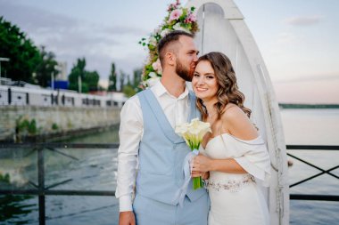 Mutlu yeni evliler öpücüğü. Rıhtımda suyun kenarında güzel bir düğün töreni.. 