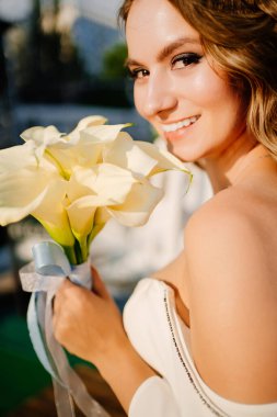 Güneş parlaması. Uzun bukleli, beyaz, zarif elbiseli, zambaklı gelin..