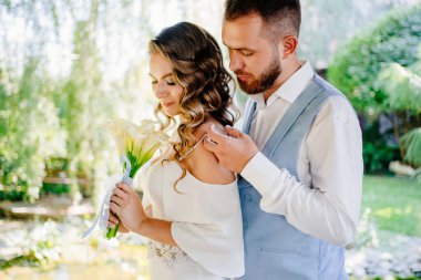 Mavi elbiseli damat nazikçe omuzlarına sarılıyor uzun bukleli geline.