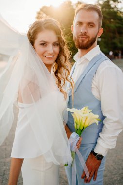 Güneş parlaması. Uzun bukleli, beyaz, zarif elbiseli, zambaklı gelin..