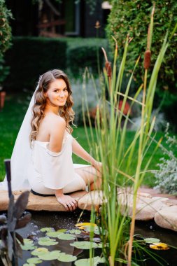 Bir yaz parkında yapay göletin yanında bukleleri olan güzel bir gelin..