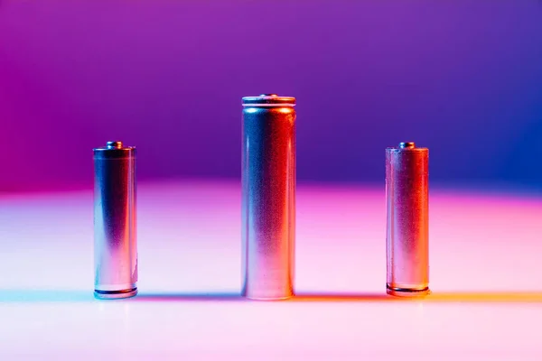 AA and 8650 Li-ion silver batteries on illuminated by multicolored light