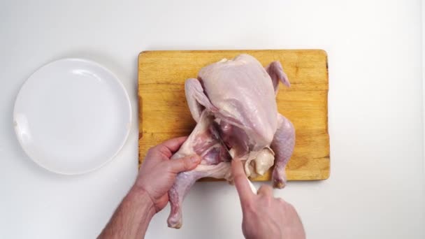 Main mâle carcasse de poulet cru boucher sur une planche à découper en bois — Video