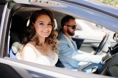 Mavi takım elbiseli damat ve siyah arabalı şık beyaz elbiseli gelin.