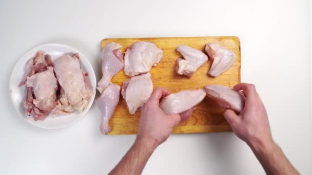 Mens hands lay out a butchered carcass of raw chicken on a wooden cutting board — Stock Video