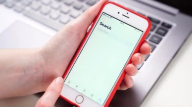 tinder. iPhone elinde dizüstü bilgisayarın önünde. Akıllı telefona uygulama yükleniyor.