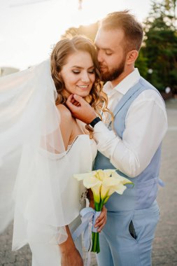 Güneş parlaması. Uzun bukleli, beyaz, zarif elbiseli, zambaklı gelin..