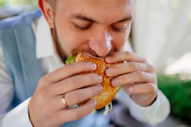 Damat eğleniyor ve hamburger yiyor. Yeni evliler için atıştırmalık.