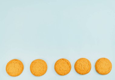 Mavi arka planda sıra sıra yulaf ezmeli kurabiyeler. Çaya tatlı ikram.