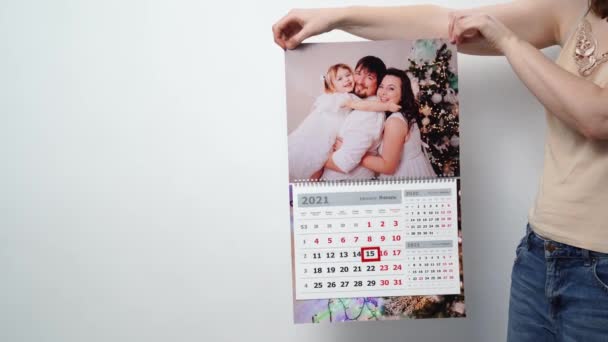 En kvinna håller det i sina händer en kalender med ett familjefoto. — Stockvideo