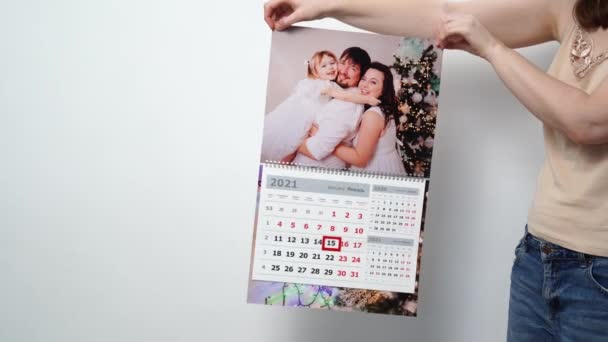 Une femme tient dans ses mains un calendrier avec une photo de famille. — Video