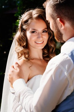 Kapat. Mutlu ve güzel gelin ve damat parkta nazikçe sarılır. dokunuş.