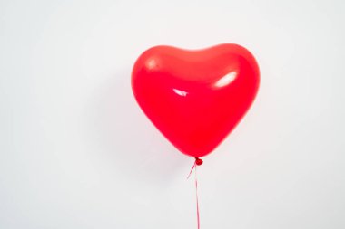 Beyaz bir duvara karşı elinde kalp şeklinde kırmızı bir balon.. 
