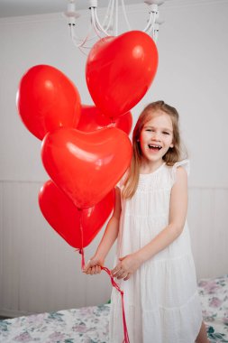 Kırmızı balonlu komik kız beyaz duvarda gülümseyen kalpler şeklinde.