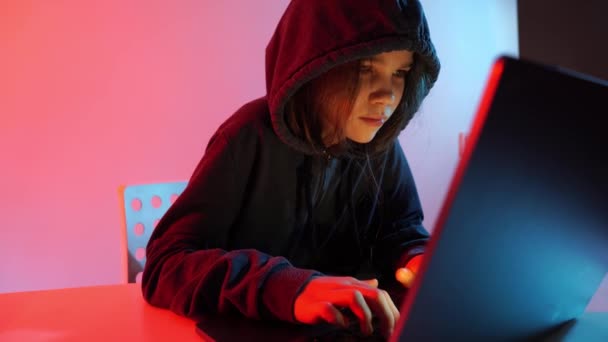 A joyful girl in dark hooded clothes works at night at the computer. Hacker. — Stock Video