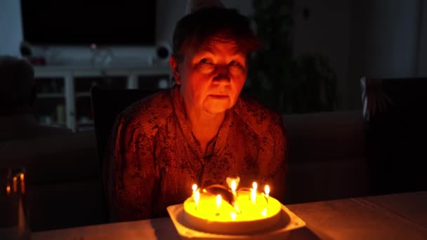 Una anciana apaga velas en el pastel de cumpleaños. — Vídeos de Stock