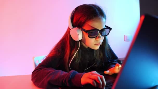 Mädchen in dunkler Kleidung, Kopfhörer und 3D-Brille arbeitet nachts am Computer. — Stockvideo
