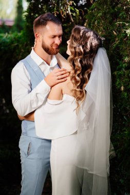 Mutlu ve güzel gelin ve damat parkta nazikçe sarılıyor.