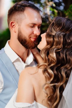 Mutlu ve güzel gelin ve damat parkta nazikçe sarılıyor.