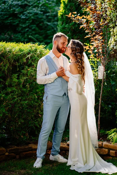 Mutlu ve güzel gelin ve damat parkta nazikçe sarılıyor.