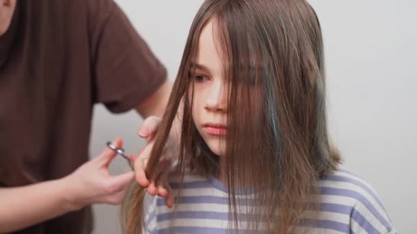 Naar de kapper. Moeder knipt haar dochters haar met een schaar. — Stockvideo