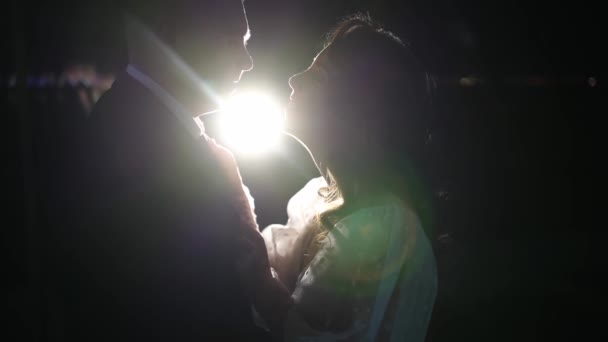 Silhouetten zoenen de bruid en bruidegom in het donker. — Stockvideo