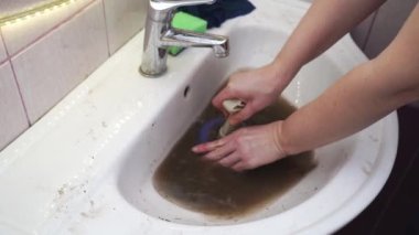 Kadın lavabodaki tıkanıklığı temizlemek için pompa kullanıyor..