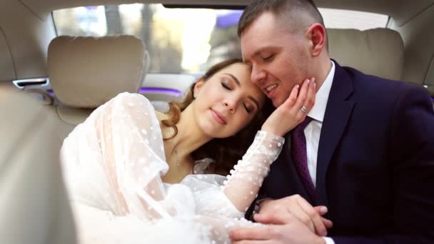 A noiva e o noivo abraçam suavemente enquanto estão sentados no carro. — Vídeo de Stock