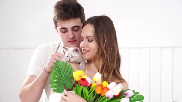 Um homem deu a sua amada mulher um buquê de tulipas coloridas e um gatinho branco. — Vídeo de Stock