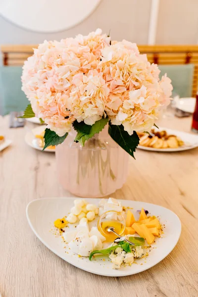 Mesa de servir con ramo de flores rosadas, aperitivos y ensaladas para las vacaciones. — Foto de Stock