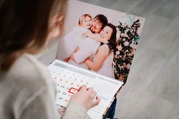 Uma mulher olha para um calendário com uma foto de família. — Fotografia de Stock