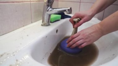 Kadın lavabodaki tıkanıklığı temizlemek için pompa kullanıyor..