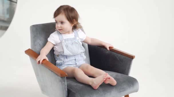 Mała dziewczynka siedzi na krześle, zaczyna się ruszać, wstaje i wychodzi. — Wideo stockowe