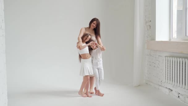 Мама и дочери позируют в белой фотостудии для фотосессии. за кулисами. — стоковое видео