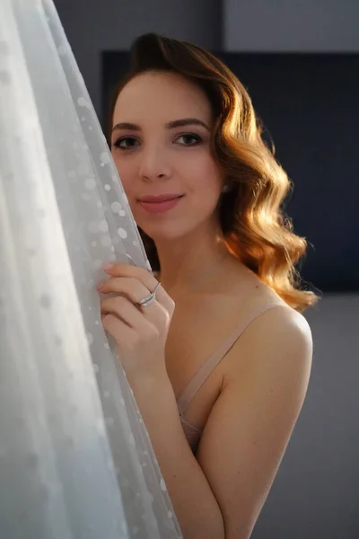 Noiva com cabelo comprido em roupa interior ao lado de um vestido de noiva branco — Fotografia de Stock